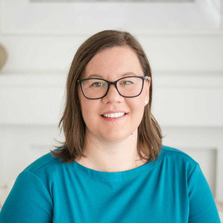 A close-up photo of Jenny, who is smiling, and wears glasses.